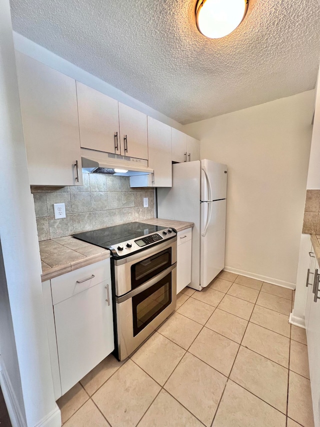 kitchen with white cabinets, decorative backsplash, light tile patterned floors, and double oven range