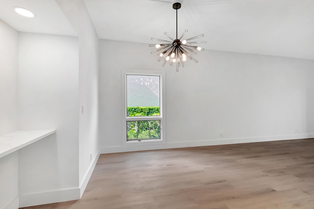 spare room featuring wood-type flooring and a notable chandelier