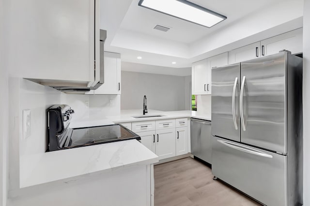 kitchen with stainless steel appliances, a sink, visible vents, light wood-style floors, and white cabinets