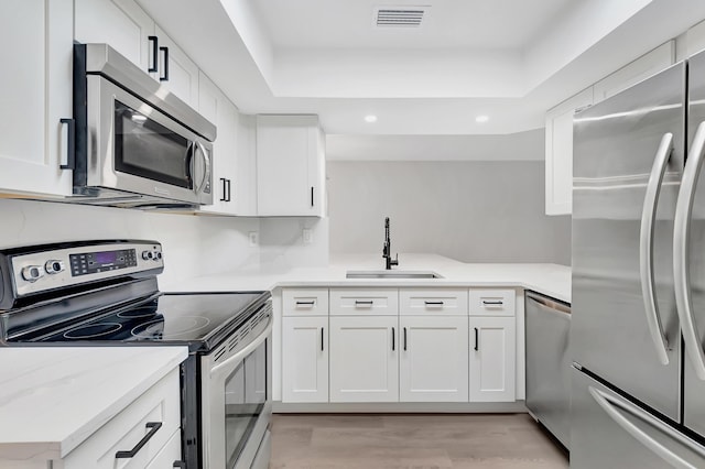 kitchen with stainless steel appliances, visible vents, a sink, and white cabinetry