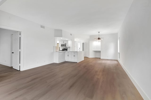 unfurnished living room featuring dark hardwood / wood-style flooring and an inviting chandelier