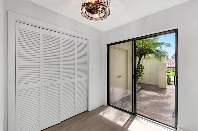 doorway to outside with a notable chandelier, baseboards, and wood finished floors