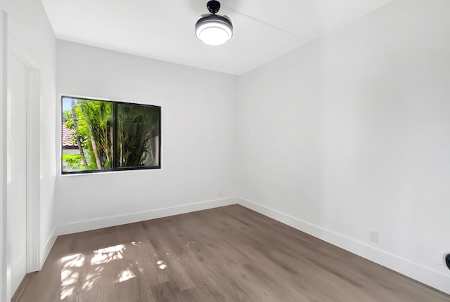 spare room with baseboards and wood finished floors