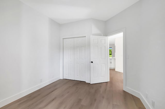 unfurnished bedroom featuring a closet, wood finished floors, and baseboards