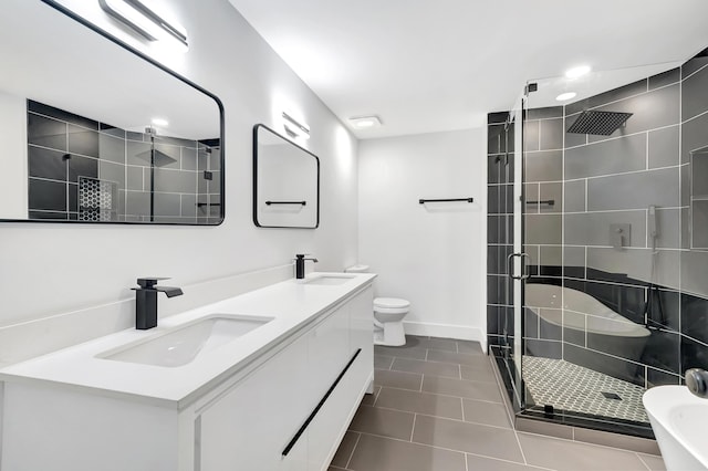 full bathroom featuring double vanity, a sink, toilet, and a shower stall