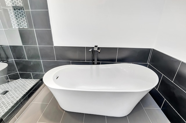 full bathroom with tiled shower, a freestanding bath, and tile walls