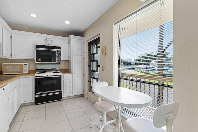 kitchen with a textured ceiling, white cabinetry, a healthy amount of sunlight, and white appliances