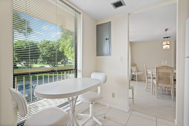 tiled dining room with a textured ceiling and electric panel