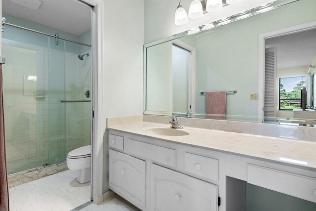 bathroom featuring tile patterned floors, vanity, toilet, and walk in shower