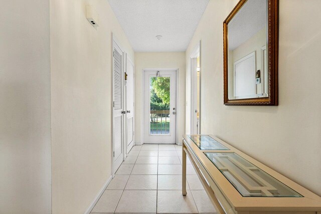 doorway to outside featuring light tile patterned flooring and a textured ceiling