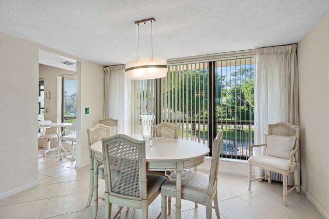 dining space with light tile patterned floors, a healthy amount of sunlight, and a textured ceiling