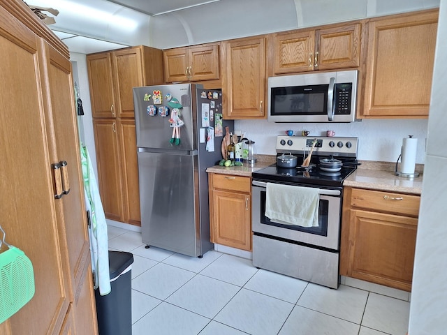 kitchen with light tile patterned floors and stainless steel appliances