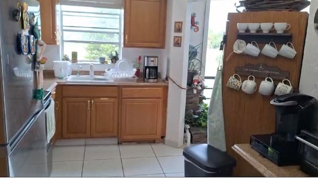 kitchen with stainless steel refrigerator, sink, and light tile patterned flooring