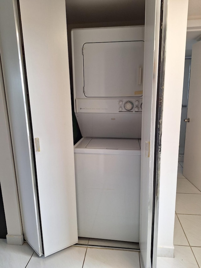 laundry room with light tile patterned floors and stacked washing maching and dryer