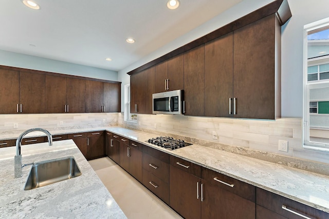 kitchen with black gas cooktop, light stone counters, tasteful backsplash, and sink