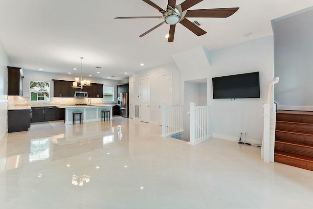 living room featuring light tile patterned floors, ceiling fan with notable chandelier, and sink