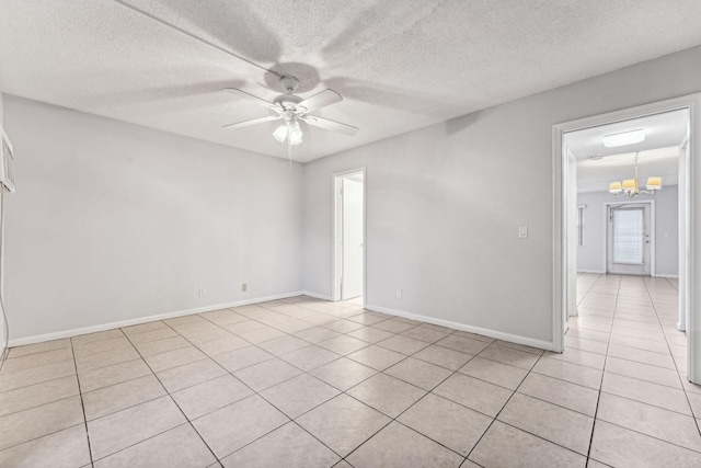 tiled empty room with ceiling fan with notable chandelier and a textured ceiling