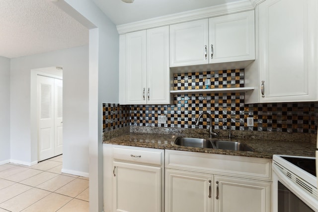 kitchen featuring white cabinetry, sink, tasteful backsplash, dark stone counters, and light tile patterned flooring