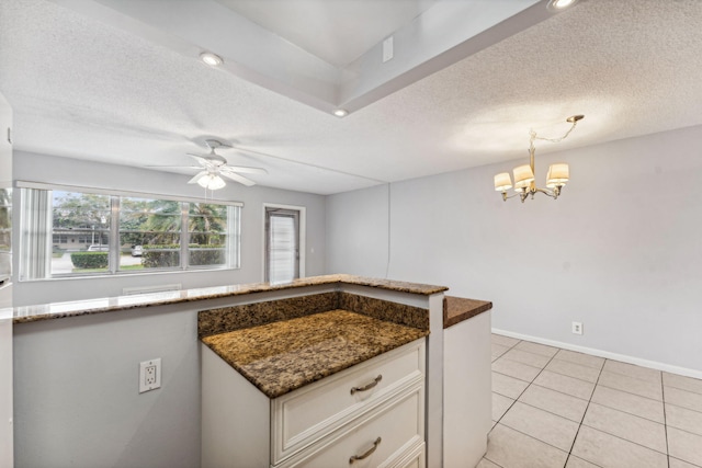 kitchen featuring dark stone counters, ceiling fan with notable chandelier, light tile patterned floors, decorative light fixtures, and white cabinets