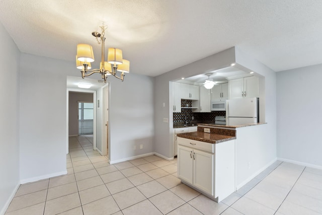 kitchen with white appliances, white cabinets, ceiling fan with notable chandelier, decorative backsplash, and decorative light fixtures