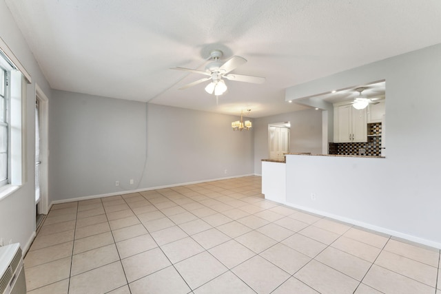 tiled empty room with a wealth of natural light and ceiling fan with notable chandelier