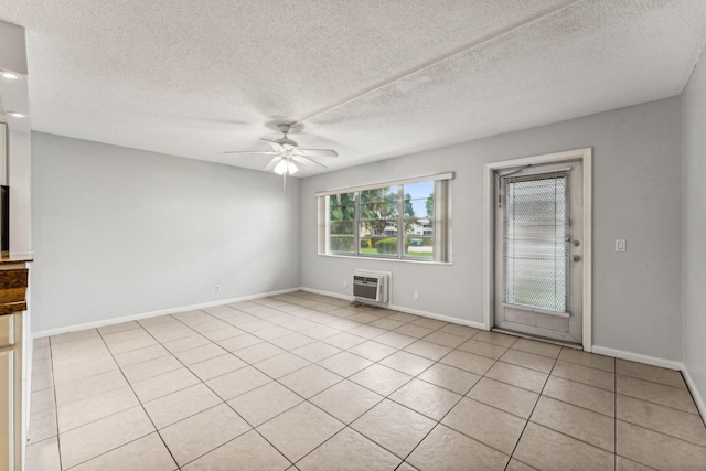 tiled spare room with ceiling fan, an AC wall unit, and a textured ceiling