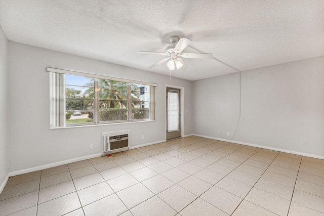 tiled empty room featuring a wall mounted AC, ceiling fan, plenty of natural light, and a textured ceiling