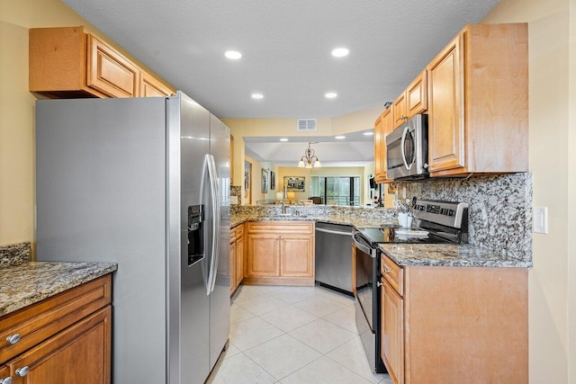 kitchen featuring light stone countertops, appliances with stainless steel finishes, backsplash, sink, and light tile patterned floors