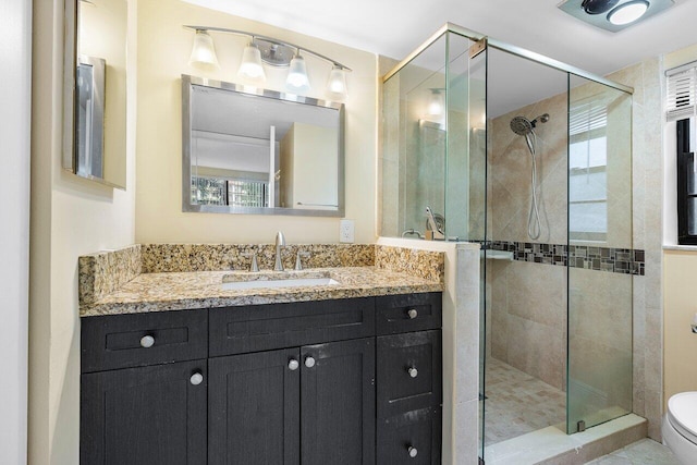 bathroom featuring vanity, toilet, and a shower with door