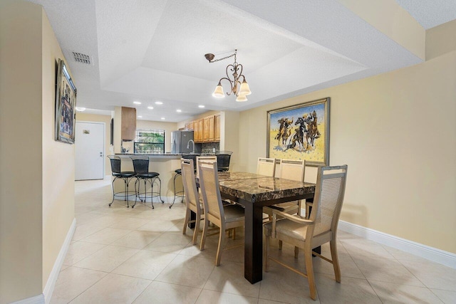 dining room with a raised ceiling, light tile patterned flooring, a textured ceiling, and a notable chandelier