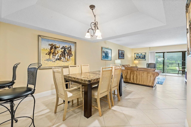 dining room featuring a textured ceiling, an inviting chandelier, a raised ceiling, and light tile patterned flooring