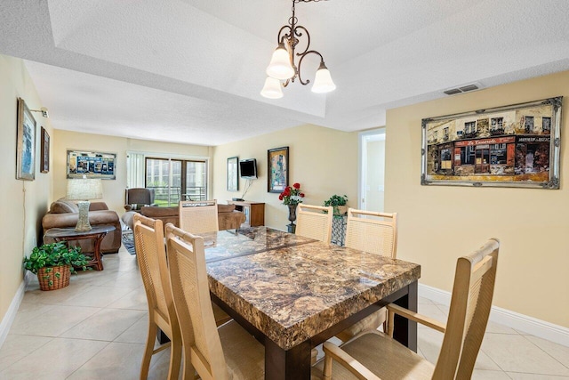 dining space featuring light tile patterned flooring, a textured ceiling, and an inviting chandelier