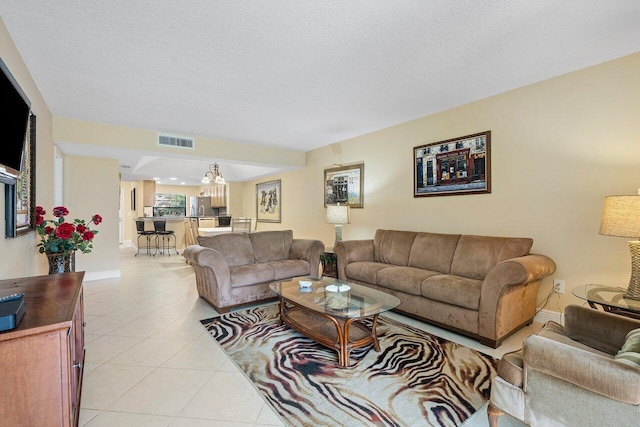 living room with light tile patterned floors, a textured ceiling, and a notable chandelier