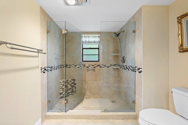 bathroom with tile patterned floors, a shower with shower door, and toilet