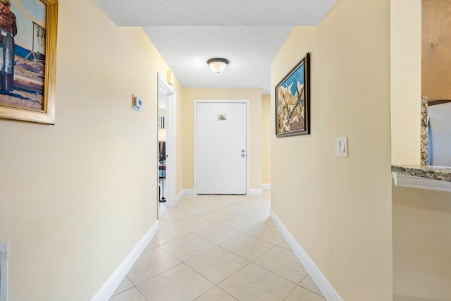 hallway featuring a textured ceiling and light tile patterned flooring