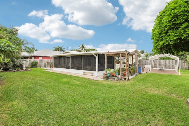 rear view of property featuring a patio area, a sunroom, and a yard