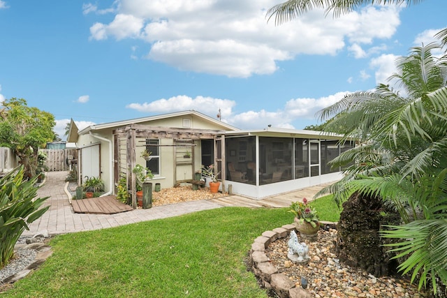 rear view of house featuring a lawn, a patio area, and a sunroom