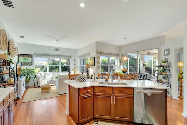 kitchen with stainless steel dishwasher, a healthy amount of sunlight, light hardwood / wood-style floors, and pendant lighting