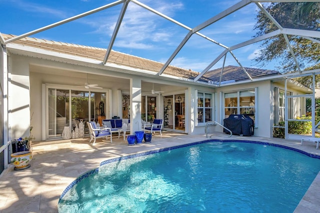 view of swimming pool featuring glass enclosure, ceiling fan, and a patio area