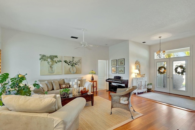 living room with french doors, wood-type flooring, and ceiling fan with notable chandelier