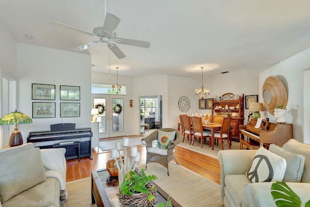 living room with french doors, ceiling fan with notable chandelier, and light hardwood / wood-style flooring