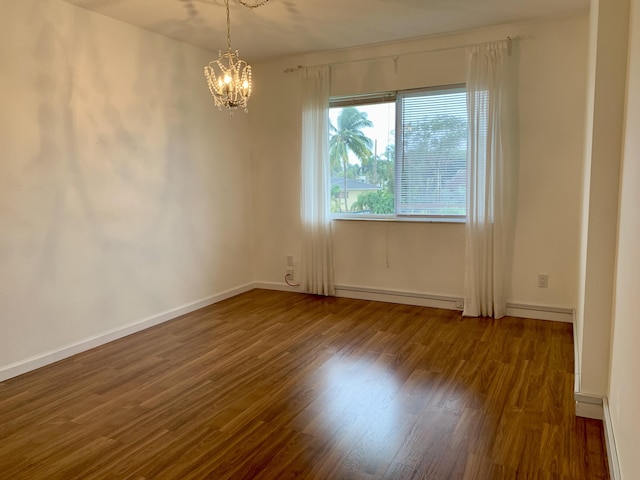 spare room featuring dark wood-type flooring, a baseboard radiator, and a chandelier