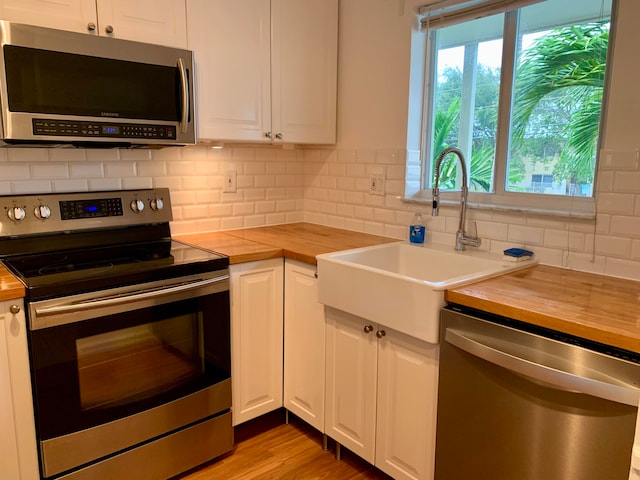 kitchen featuring sink, stainless steel appliances, wooden counters, backsplash, and white cabinets