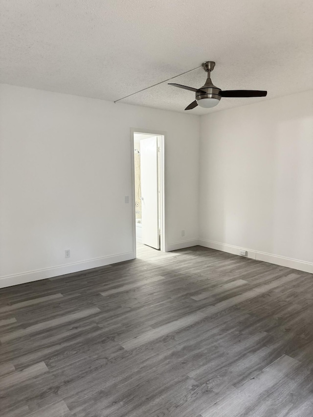 spare room featuring a textured ceiling, baseboards, and dark wood-style flooring