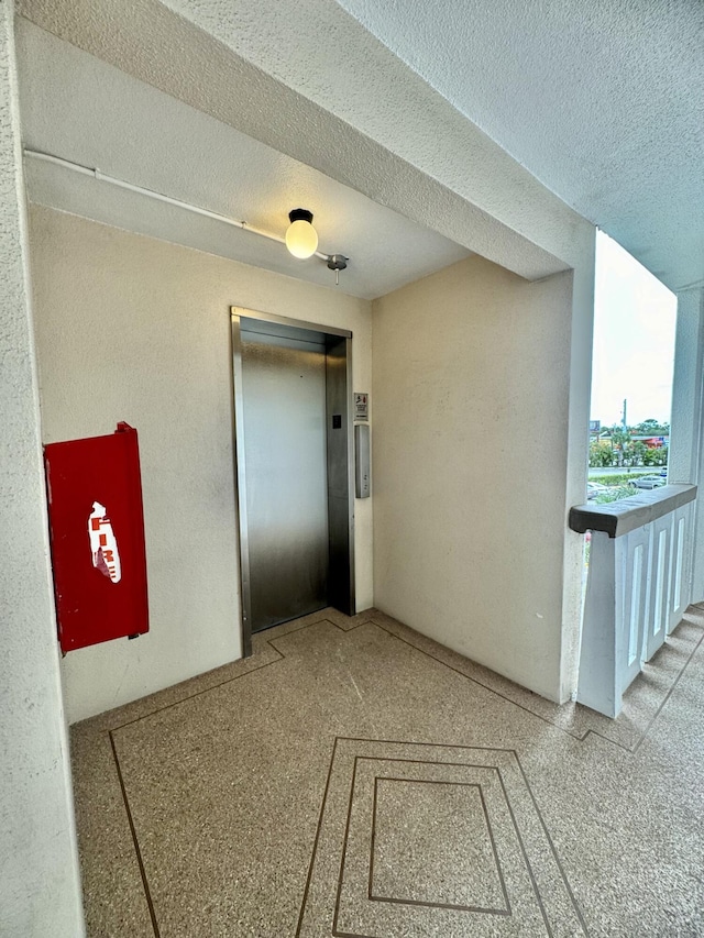 hall featuring elevator and a textured ceiling