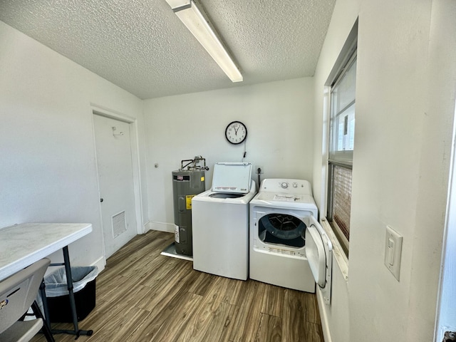 laundry room featuring laundry area, visible vents, dark wood-style flooring, washing machine and clothes dryer, and electric water heater