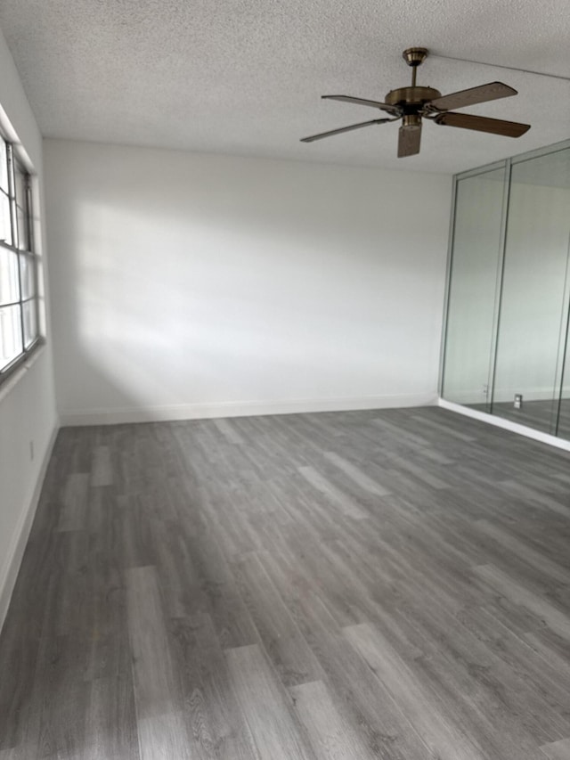 interior space with a textured ceiling, dark wood finished floors, and baseboards