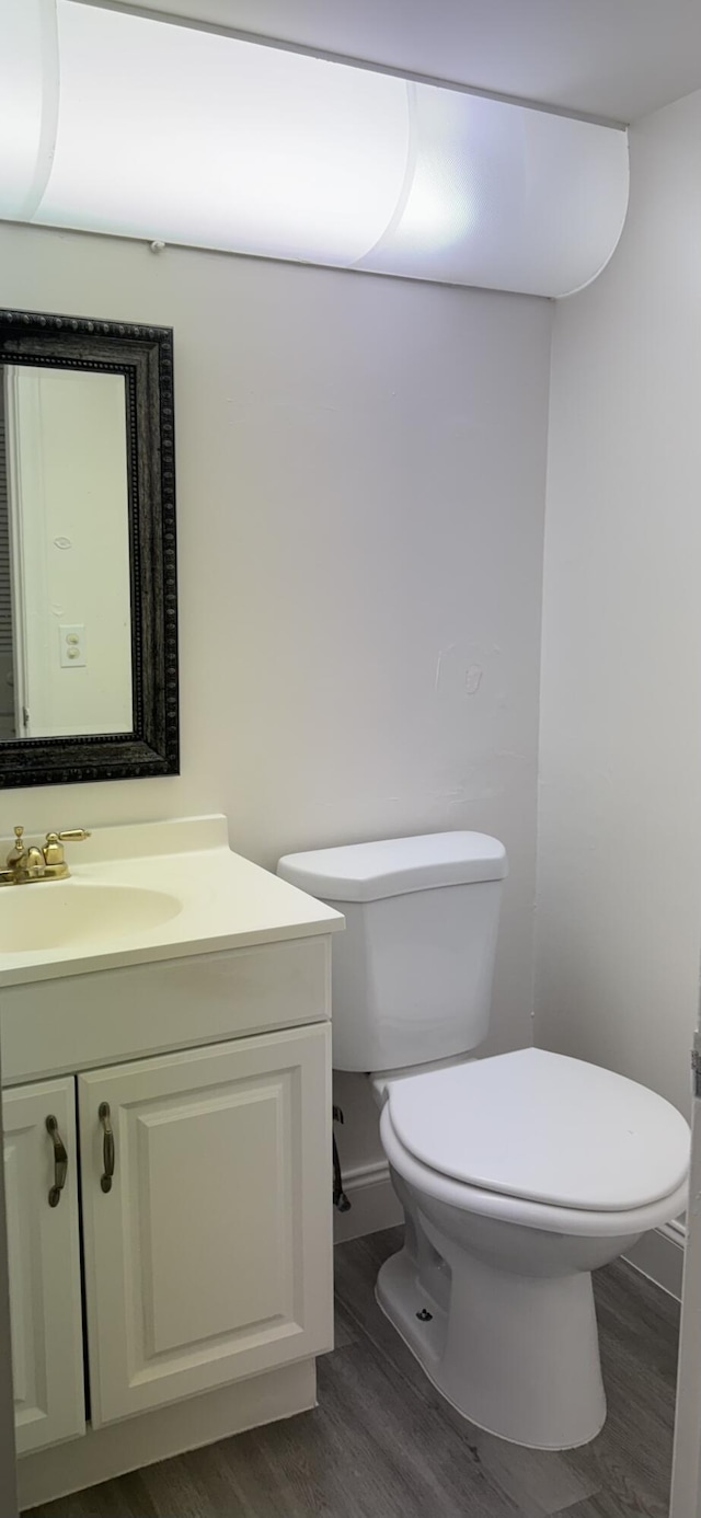 bathroom featuring toilet, wood finished floors, and vanity