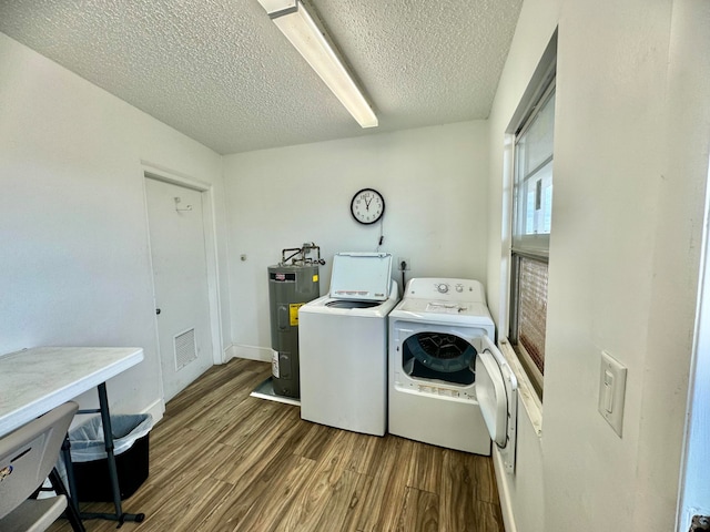 clothes washing area featuring hardwood / wood-style floors, independent washer and dryer, a textured ceiling, and water heater