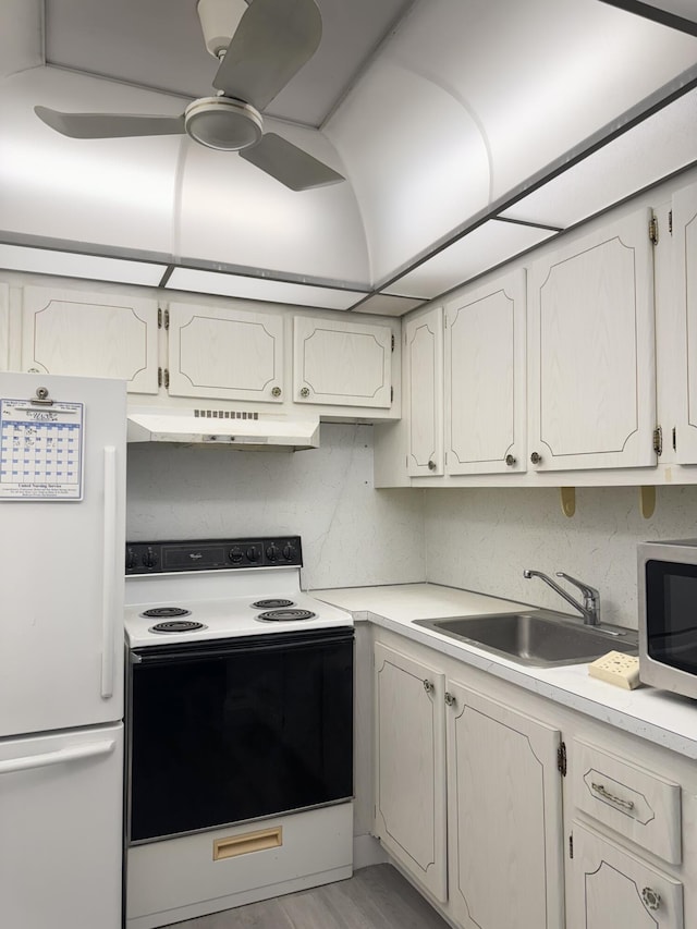 kitchen with light countertops, electric range, freestanding refrigerator, a sink, and under cabinet range hood